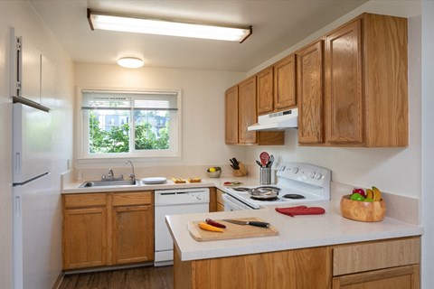 a kitchen with wooden cabinets and white appliances and a window